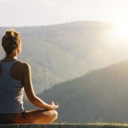 Junge Frau meditiert vor wundervoller Naturkulisse, Foto zum Blogeintrag über Yoga bei JOYA International Massageprodukte
