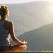 junge Frau meditert vor wundervoller Naturkulisse, Foto zum Blogeintrag bei JOYA International über YOGA