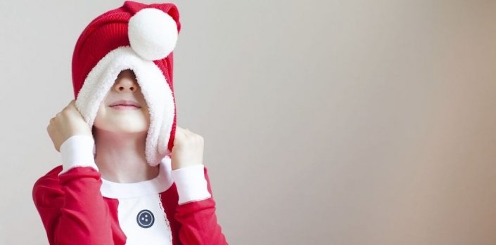 Weihnachten mit JOYA Kind zieht sich Weihnachtsmütze über den Kopf- zu viel gegessen, gehört oder ist ihm alles zu viel?